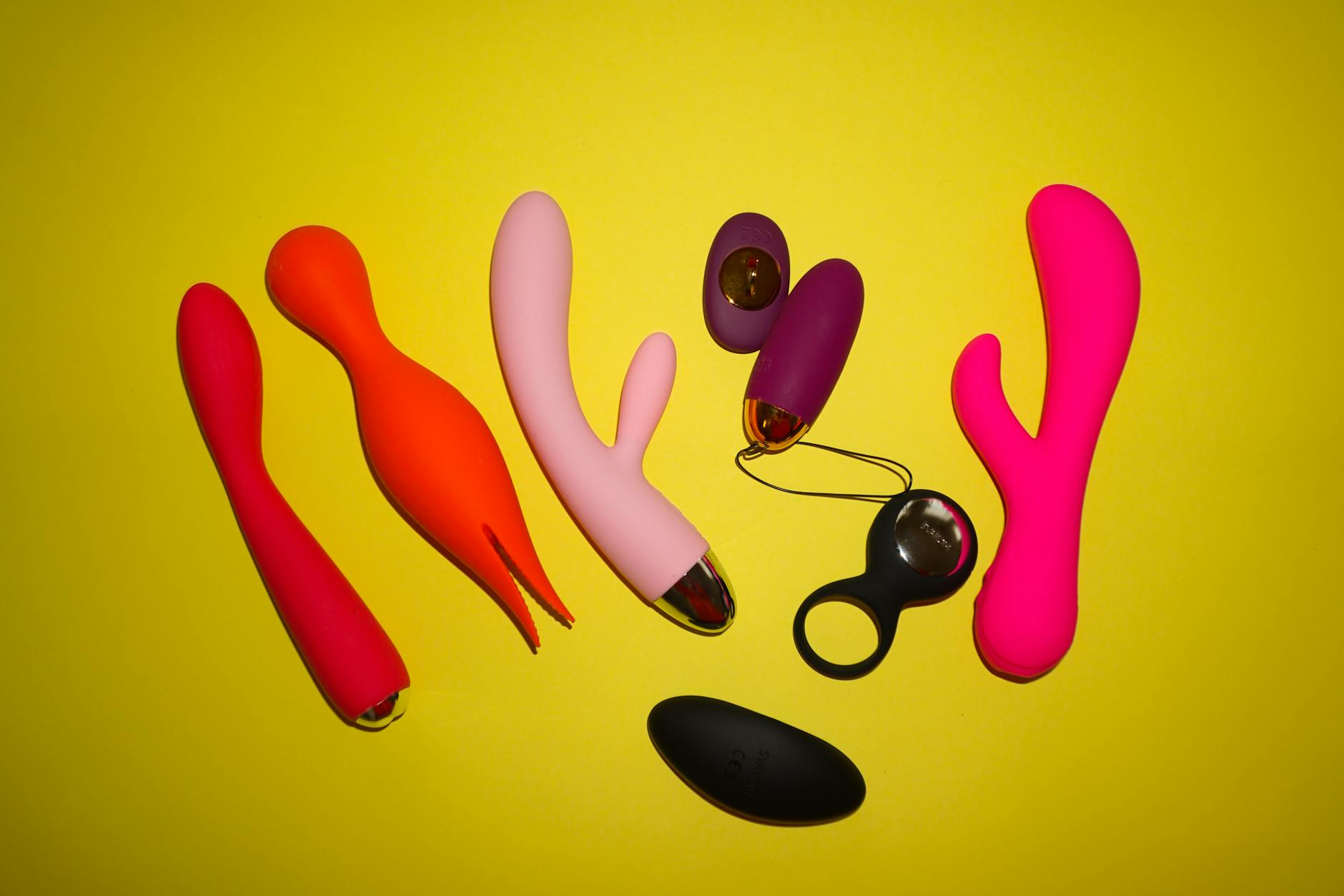 A yellow silicone vibrator surrounded by creative elements on a bright background