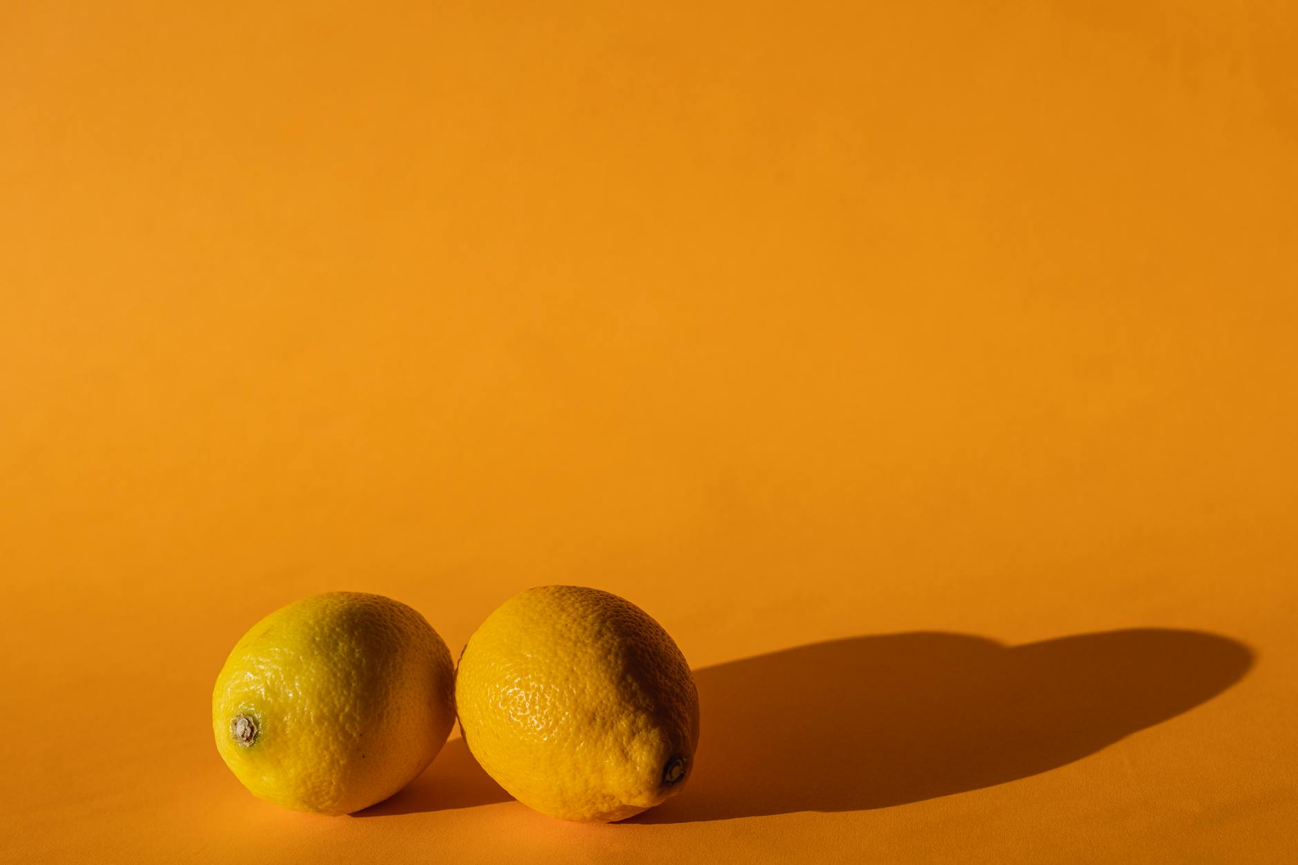 Ripe vivid lemons composed on yellow background in bright daylight, symbolizing fresh sensation